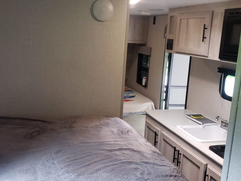 Comfy bunk beds maximize the sleeping capacity of this small trailer. View of the kitchen including microwave and lots of storage.