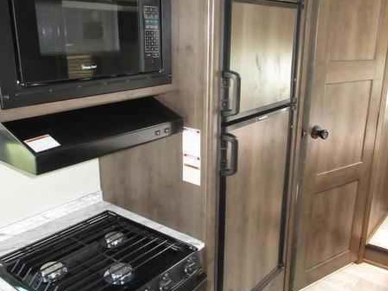 Kitchen area with microwave, stovetop, oven, and refrigerator
