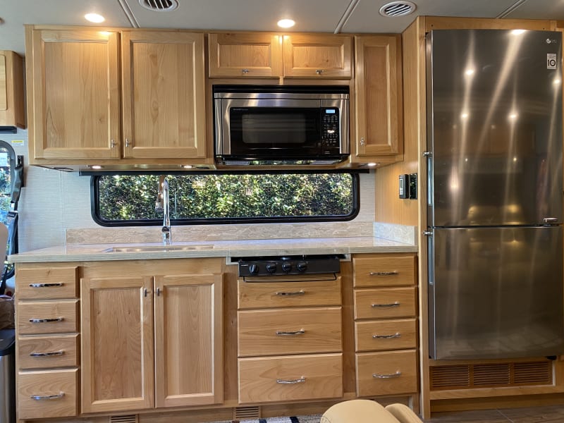 Generous counter/meal preparation space with apartment size refrigerator/freezer, three-burner stovetop, and combo microwave/convection oven.