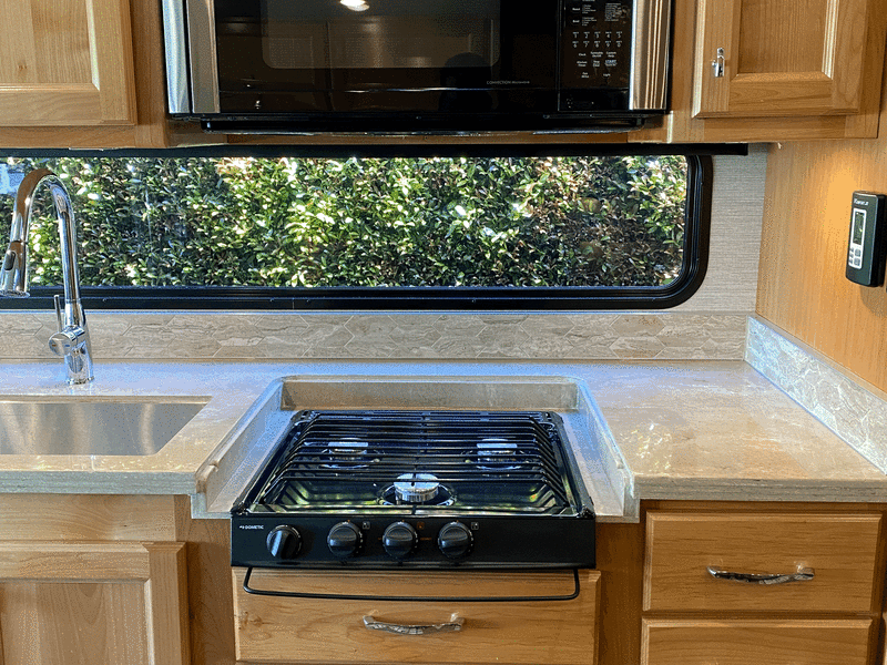 Generous counter/meal preparation space with apartment size refrigerator/freezer, three-burner stovetop, and combo microwave/convection oven.