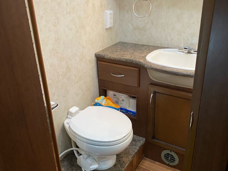 Bathroom with sink, RV Toilet and storage. 