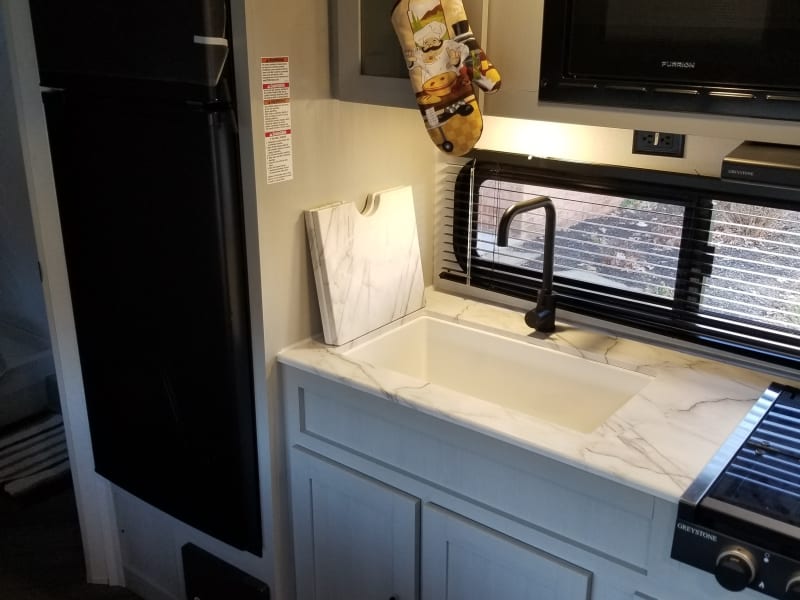 A marble base sink with optional covering for extra counter space. Large refrigerator with various kitchenware available.