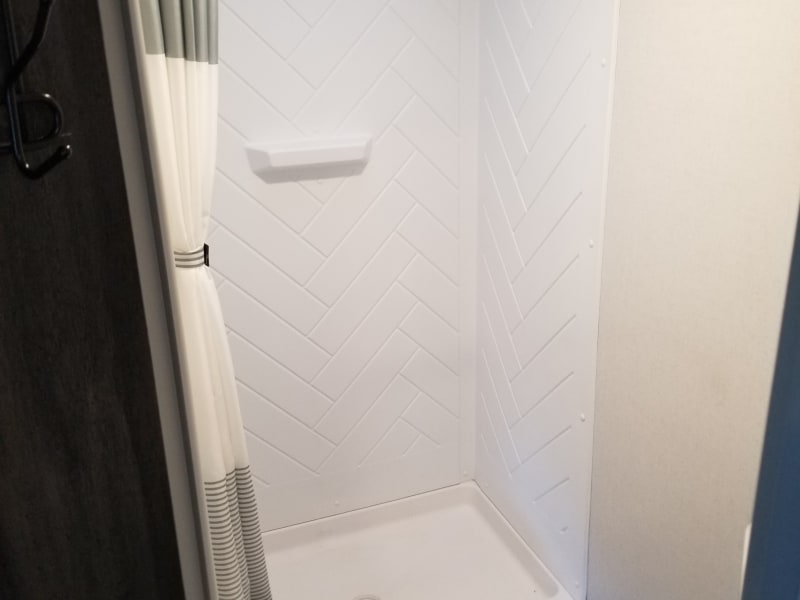 Large scale shower with herringbone tile walls and slip resistant flooring, deluxe shower curtains. 