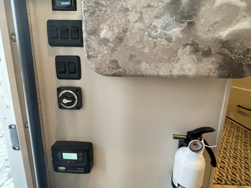 Main power supply switch, light switches, solar controller display, and fire extinguisher