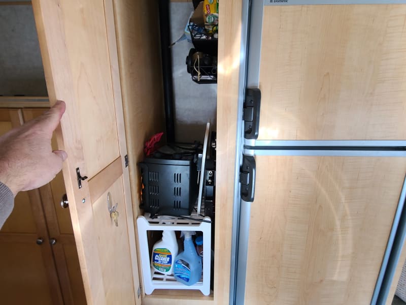 Small pantry next to refrigerator.  Hold griddle, some cookware and basic cleaning supplies