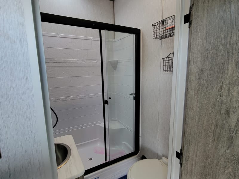 This roomy shower has a super high ceiling and a double sliding glass door. And the bathroom has a real porcelain toilet!