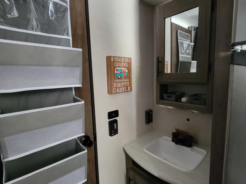 Sink and mirror are across from bunks. Toilet and shower are enclosed by door. 