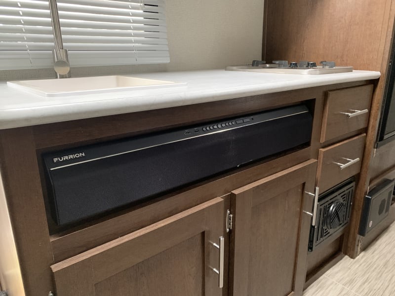 Indoor Bluetooth sound bar. Controls interior and exterior speakers. Kitchenette area, sink, stove.