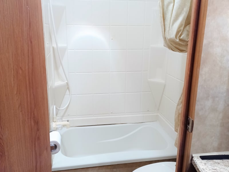 Small tub with shower. Toilet. 