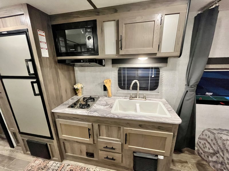 You can see the double bowl kitchen sink along with the 2-burner stovetop and microwave. Also see all the storage places!