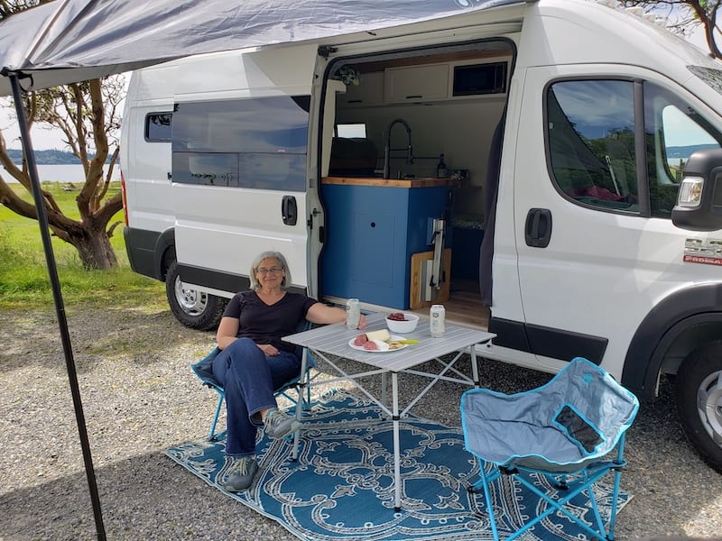 Exterior set up with Moonshade awning, and rug. (2) camping chairs and table can be rented for additional comfort.