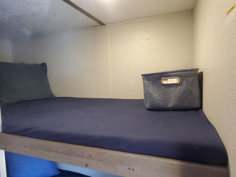 Bunk Beds with sheets, storage baskets, standard pillows and decorative pillows featured in the Glamping Package Addon