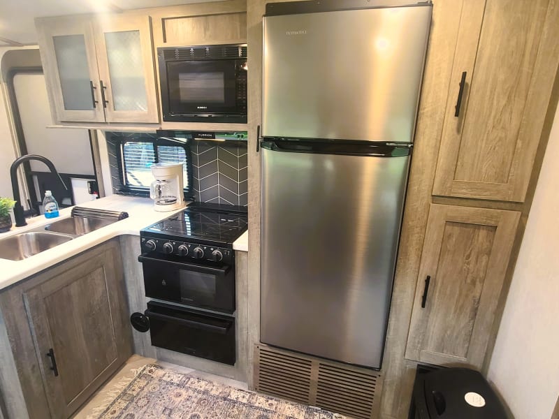 Gas stove and oven, microwave, and large refrigerator, as well as storage cabinets and pantry. 
