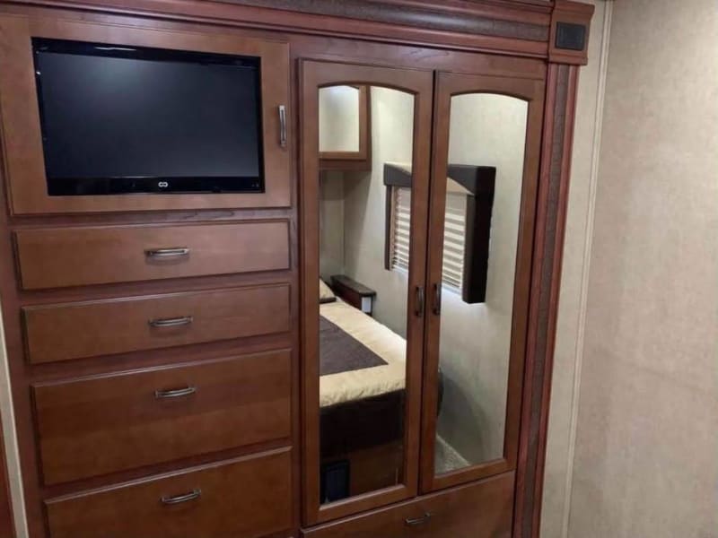 Cabinets and drawers in master bedroom. The TV is encased within the cabinet door, leaving most of the cabinet for other storage. 