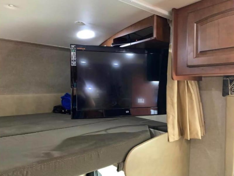 32in TV on motorized swivel over cab. TV is plugged into an outlet that automatically switches between vehicle and house power.