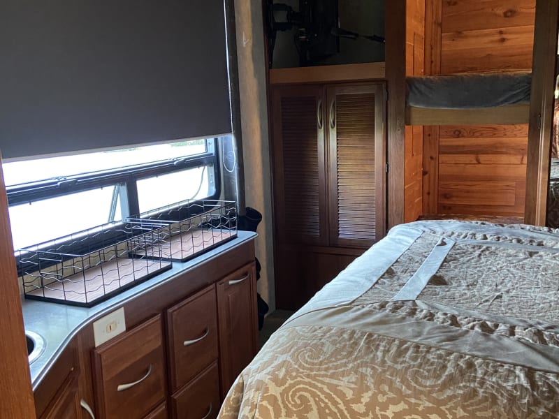 Bedroom area with bunks on back wall and washer/dryer combo under tv mount