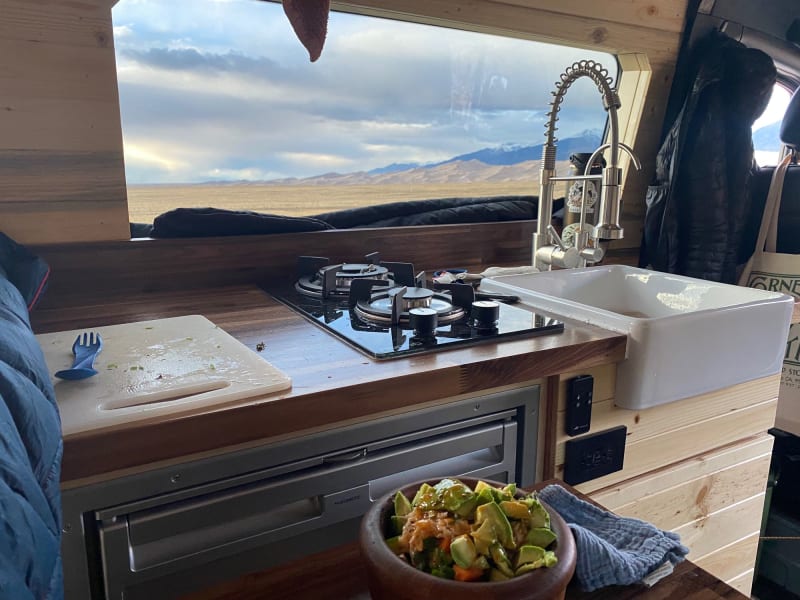 Dinner looking out over Great Sand Dunes National Park in Colorado. You can see the spacious fridge, gas stove, and sink. With a view!
