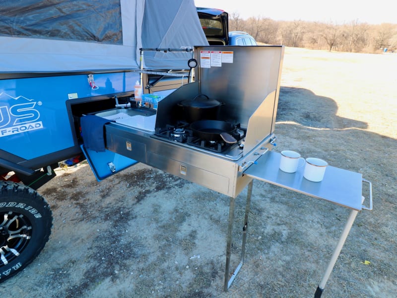 outdoor kitchen with 4 propane burners, sink, spice rack, and two prep areas