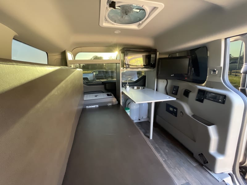 Couch, TV, microwave, and folding table near sink