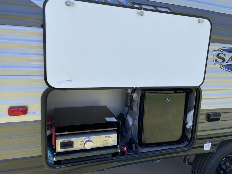 Outdoor kitchen includes propane griddle and mini fridge.