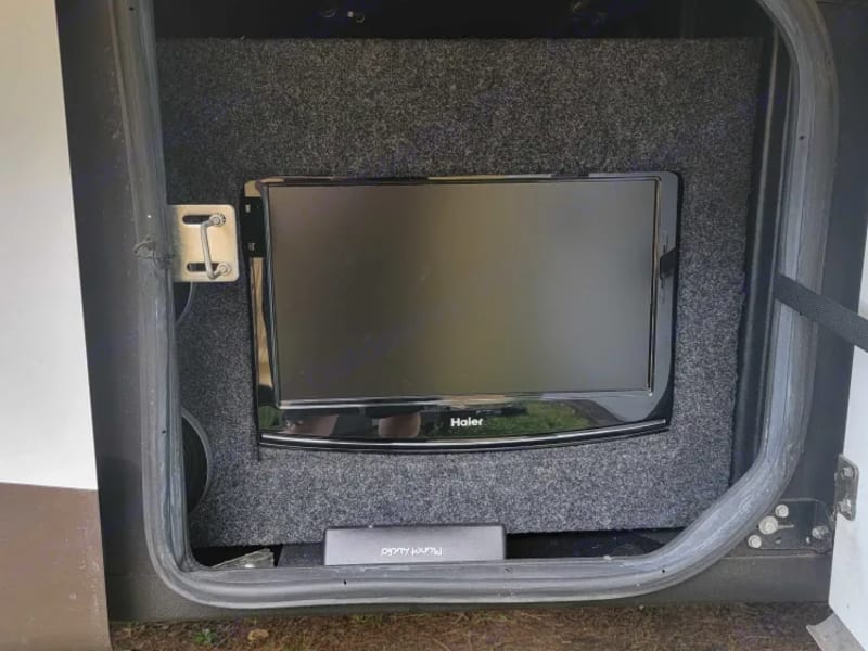 Outdoor TV next to outdoor mini fridge. There's a lot of outdoor space. 