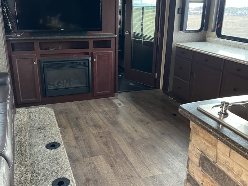 Entertainment center, couch, fireplace and option for a dining table next to the couch. Lots of storage in cupboard across from the couch.