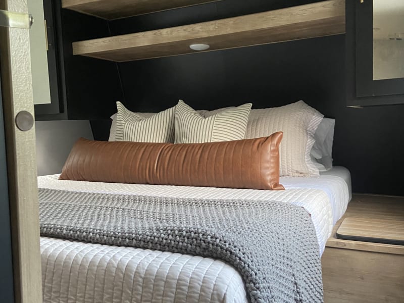 Queen bed located in privacy room. Storage is available within nightstands, within cabinets, on top of shelves and under bed. 