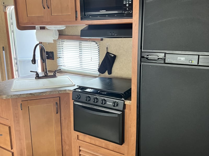 Kitchen area with refrigerator, microwave, stove, oven, sink, storage