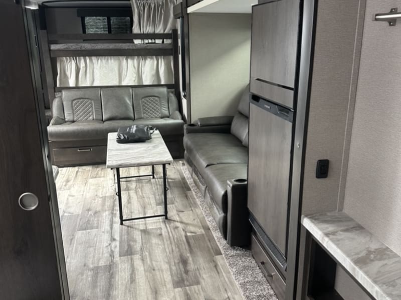 Lounge area with double bunk beds in back, fold-out couch and recliners on the right 