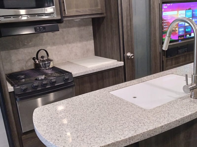 Excellent view of the stove, microwave and kitchen island work area. It also shows the frosted glass door to the pantry.