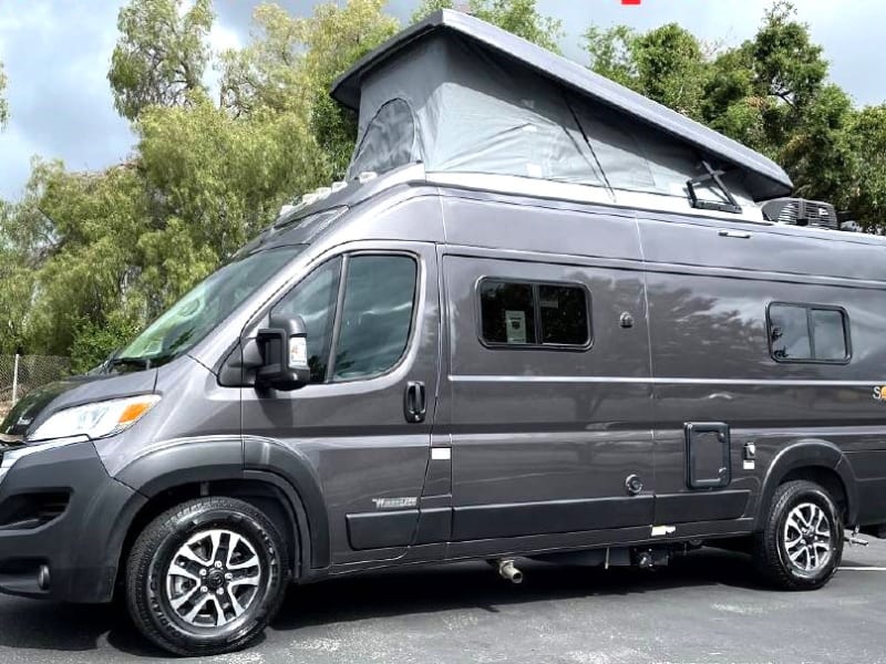 Capture the essence of adventure with a stunning exterior shot of our RV's driver's side featuring a pop-up top. 