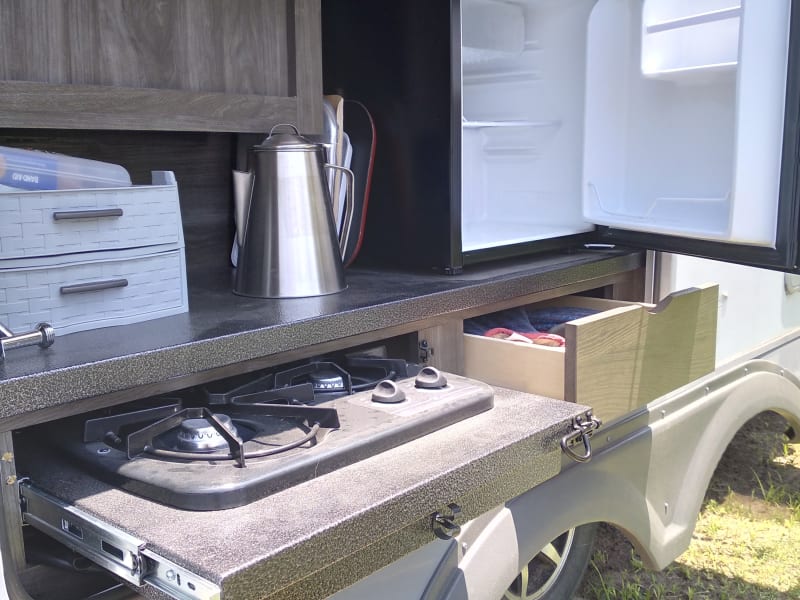 The outdoor kitchen has a 2-burner stove top, refrigerator, a faucet w/spray attachment and storage for Grilling supplies. 