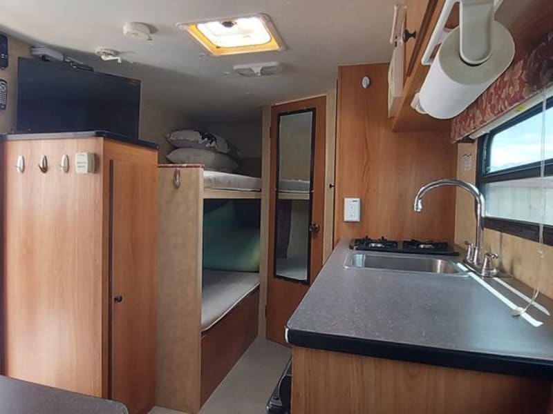 View of kitchen from dinette:   countertop for food prep, bunk beds, and tv.