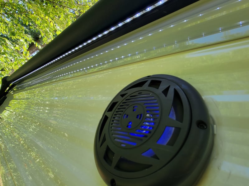 The awning has LED lights, and the outdoor speakers are also lit.