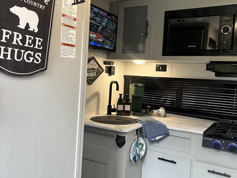 Kitchen with microwave, two burner stove, sink, large refrigerator/freezer, fully stocked with cooking utensils, plates, cups, etc