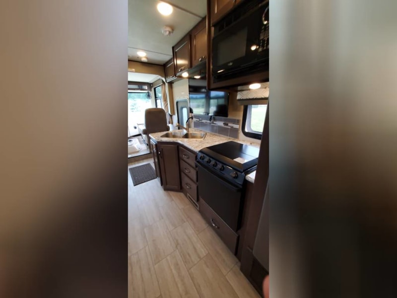 Kitchen with sink, cabinets, drawers, stove and oven. TV