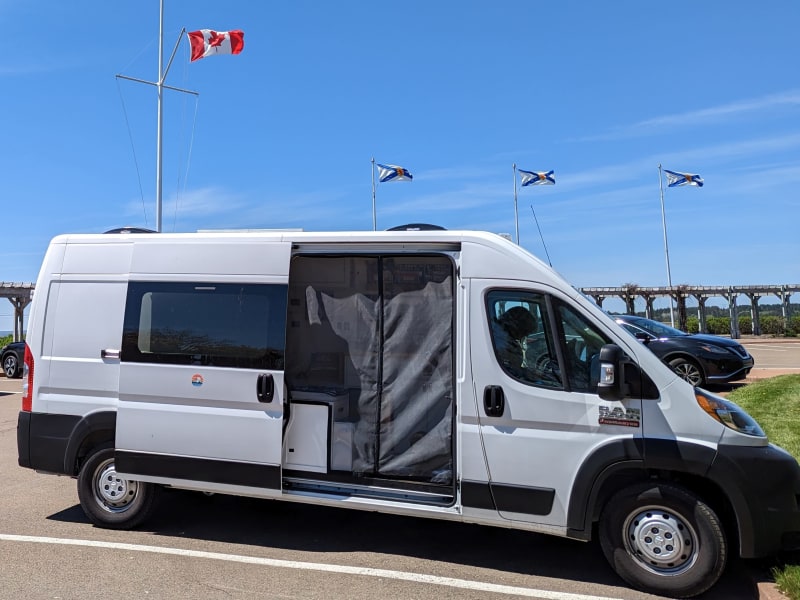 Passenger-side view; sliding door open; magnetic bug-screen closed. Note how easily we fit into standard parking space at a Canada Visitor Center!