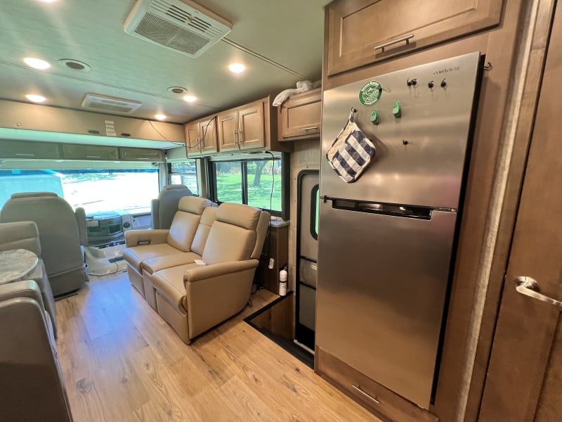 In the kitchen looking towards the cockpit. A Full-sized fridge, entry, and reclining sofa with drop down cup holders and phone charging station