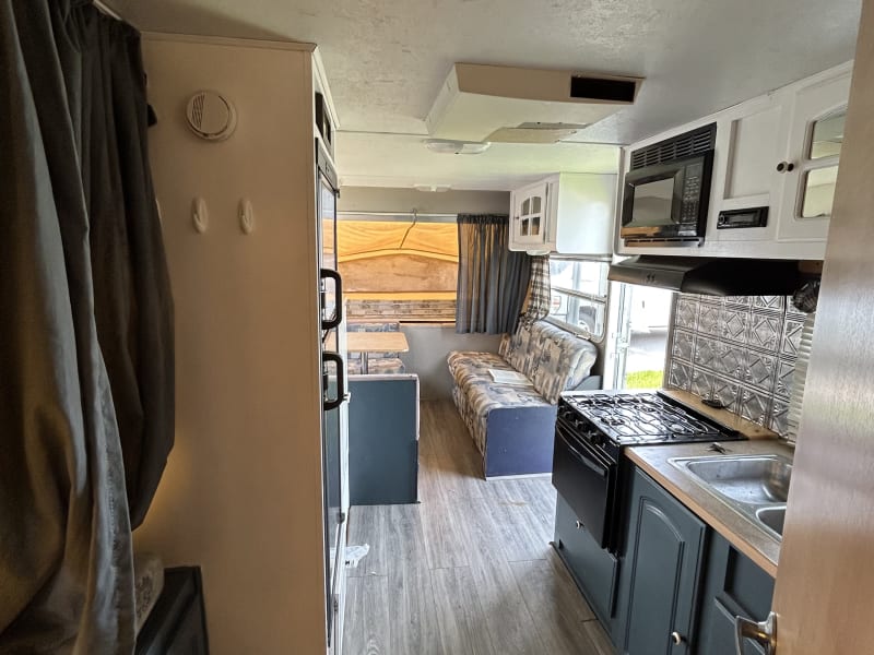 PIcture from back of camper with view of kitchenette, lounge, dinette, and front pop-out queen bed