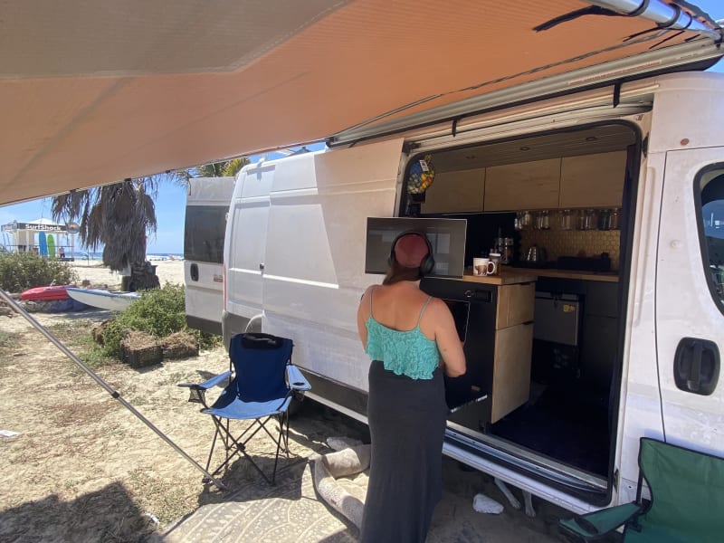 outside desk setup on the beach, awning out, camping chairs, rug