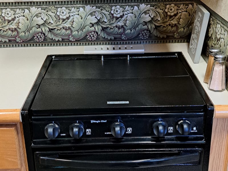 Propane stove, showing that you can have more counter space with the cover down. Burners are under the flat fold-up top.