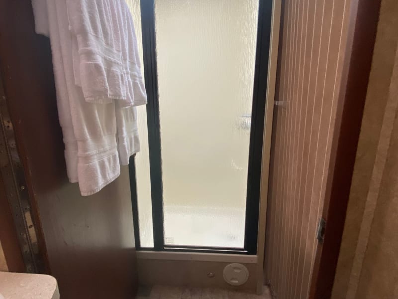 The bathroom door latches open and a closed curtain on the other side creates an open and private place to have your refreshing shower routine. 