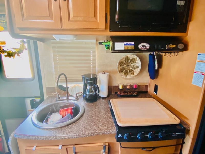 Basic essentials kitchen with a gas stovetop, microwave, and sink. Coffee and coffee pot provided in addition to basic cooking supplies