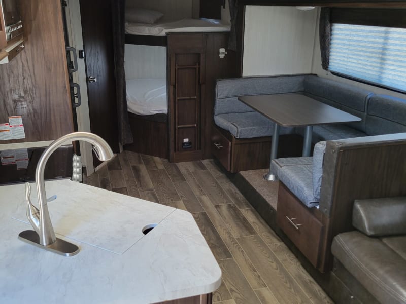 Your first view of the interior is to the left/aft end of the camper. A fully stocked kitchen and convertible dinette are ready for you to make camp meal memories with your loved ones.