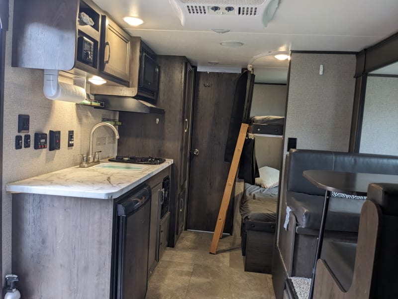 From the queen bed at the front of the camper, looking towards the back. Kitchen on left, dinning room on right, bathroom door straight back, bunk beds beside that. 