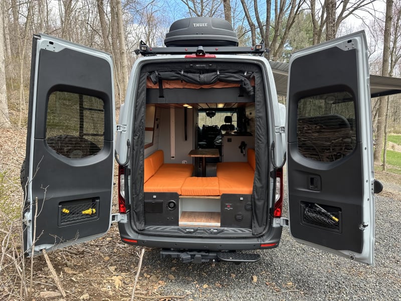 rear van view of the dinette and upper bed stored in the up position. 
