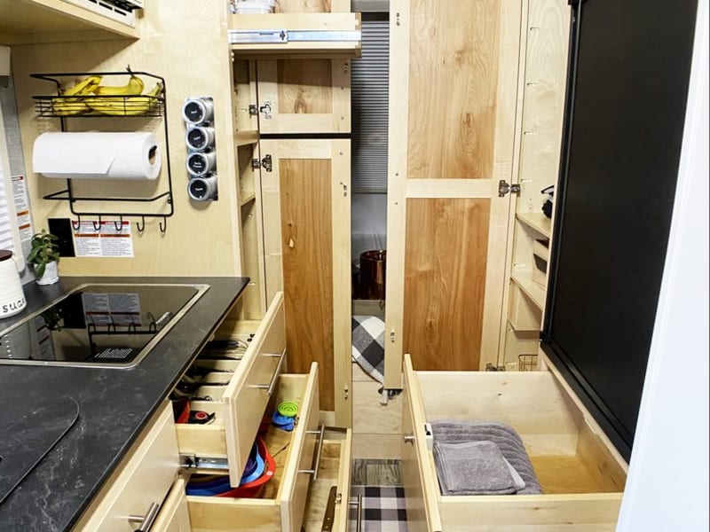 There are multiple cabinets and drawers for storage, including a pantry and clothes closet.