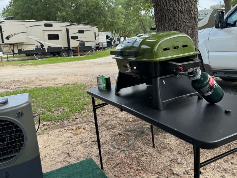 Optional grill, folding table, and outdoor rug available with this camper 