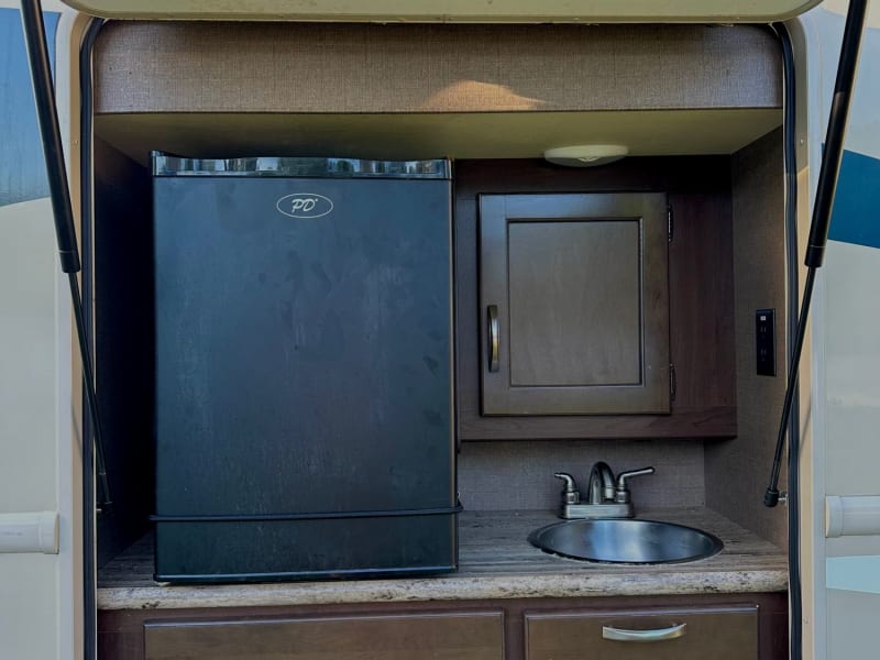 Exterior kitchen equipped with fridge, sink, and storage 
