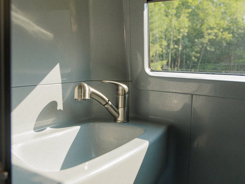 The washroom hosts a small sink, toilet and functions as a 